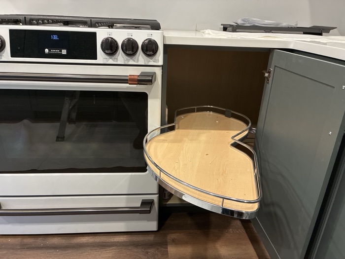 A corner cabinet pull-out extended beside a range, its tray stopped against the appliance
